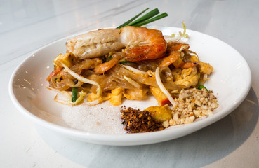 Fried Rice Sticks with Shrimp (PAD THAI GOONG SOD) put a white plate and placed on a white marble table.This is a popular food to eat when coming to Thailand.