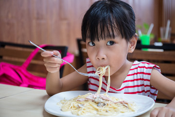 Asian Chinese little girl eating spaghetti