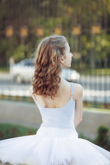 Young beautiful ballerina dancing outdoors in a park. Close up portrait young blond caucasian girl.