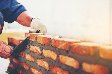 Old man Hand white-wash cement built wall brick new house, Bricklayer worker installing brick...