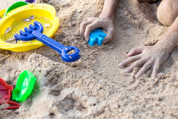 Fototapeta na wymiar close-up baby girl hand playing toys on the sand beach