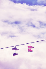 Old shoes hang on wire, color toning applied.