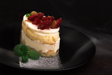 Strawberry cake with almond petals. Old black background. Close-up. Top view
