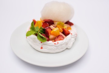 Dessert with cream, strawberries, oranges, apples and mint on white background