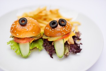 Funny baby burgers on a plate close-up with French fries and sauce