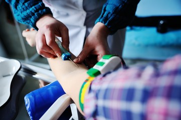 Doctor making blood analysis young girl patient. Blood sampling from a vein on the background of the clinic