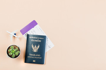 Flat lay and copy space for design work of Thailand official passport, boarding pass, small cactus and airplane on yellow pastel color background.