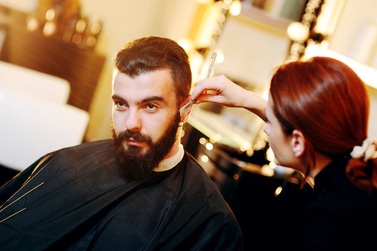 Beautiful manly bearded man in a barbershop on a beard styling