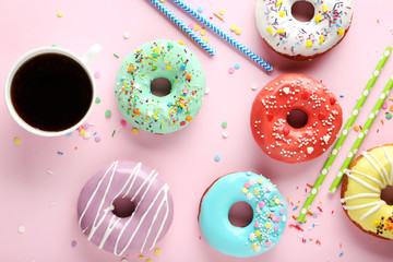 Tasty donuts with sprinkles with cup of coffee on pink paper background