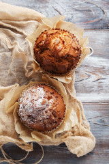 Tasty muffins with gauze fabric on wooden table