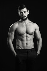 Fototapeta na wymiar Young handsome muscular man with a beard, posing on a black background