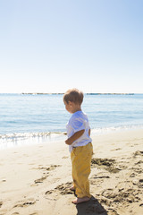Fototapeta na wymiar Little boy walking on a beautiful tropical beach