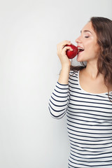 Fototapeta premium Portrait of young woman with apple on grey background