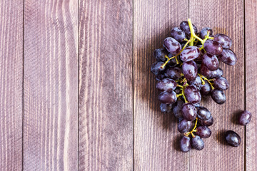 Black grape branch on dark wooden background