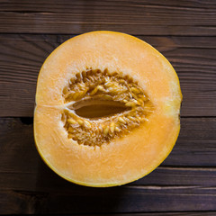 Melon cut in half on a wooden background (Top view)