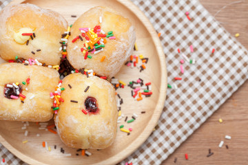 a variety of jam doughnut on wooden plate with sprinkles