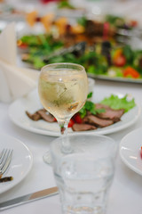 Glass filled by white wine on a restaurant table.
