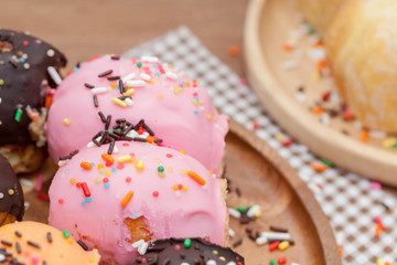 a variety of doughnut on wooden plate with sprinkles