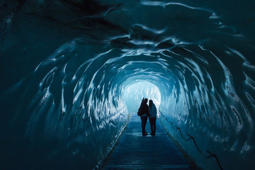 Ice cave Mer de Glace in France with two people - obrazy, fototapety, plakaty