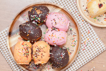 a variety of doughnut on wooden plate with sprinkles