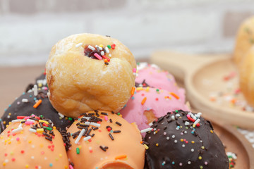 a variety of doughnut on wooden plate with sprinkles