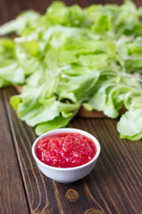 Mexican salsa or indian chutney in white ceramic bowl against green herbs