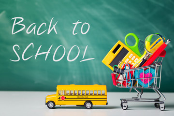 Back to school concept. School supplies, schoolbus and shopping cart with stuff