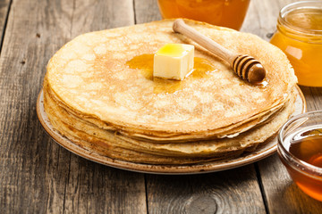 Homemade pancakes and various honey on wooden table