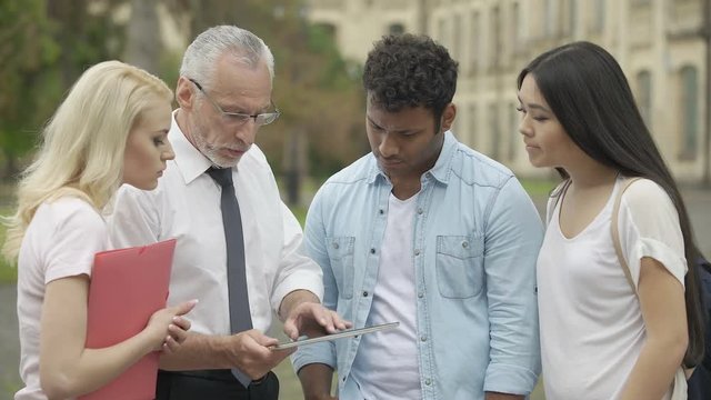 Senior teacher showing new educational app on tablet to students, MBI studies