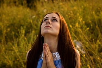 Girl praying in the garden close-up