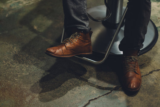 Close Up Of Boots Of Man Sitting In Barber Chair At Salon