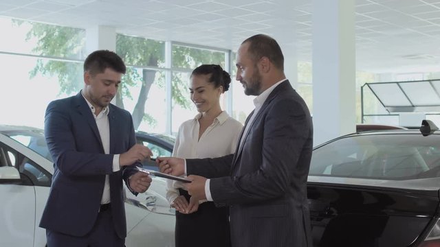 Young couple is buying a new car in the car dealership