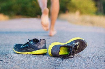 The young guy runs away from the shoes. A man runs barefoot along the road, shoes in the spotlight....