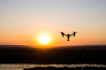 quadrocopter drone with remote control. Dark silhouette against colorfull sunset.