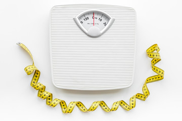 Bathroom scale and measuring tape on white background top view