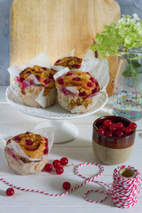 Red currant muffins on white plateau. White wooden table, gray background. Baking paper.