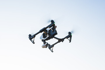 Fototapeta na wymiar White drone, quadrocopter with photo camera flying in the blue sky.