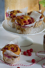 Red currant muffins on white plateau. White wooden table, gray background. Baking paper.