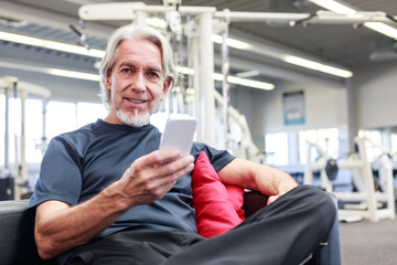 Naklejka na ściany i meble Senior Caucasian Man At The Gym, Checking His Phone