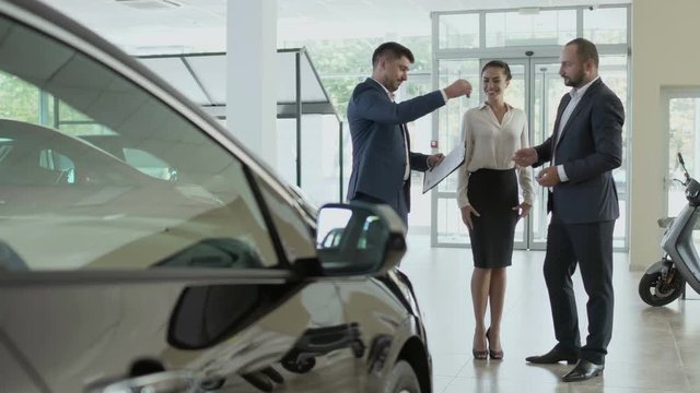 The couple signs the contract of buying car in the car showroom and gets key