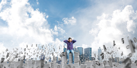 Attractive man sitting on pile of paper documents.