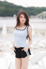 Obraz premium Summer fashion portrait of stunning woman with tanned fit sexy body, wearing white t-shirt, short denim shorts.
