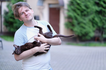 A man is holding a Siamese domestic cat in his arms