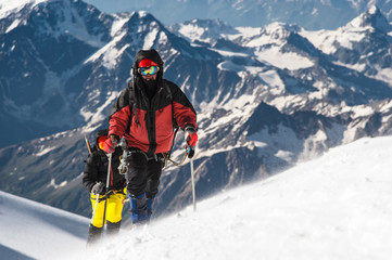 Fototapeta na wymiar The climber climbs the snow-covered summit.