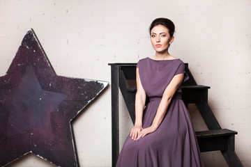 Portrait of a young woman in a long dress in minimalistic loft inteior