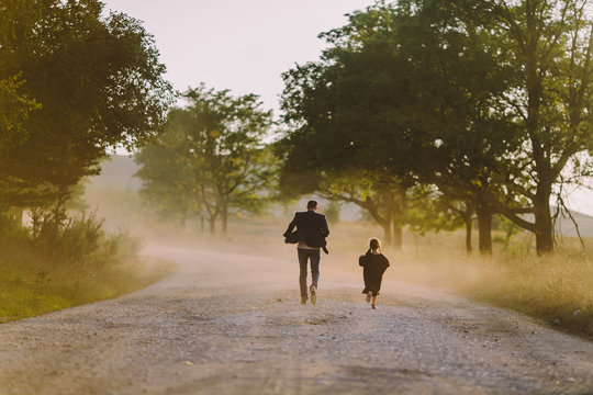 Man and little girl running away along dusty road
