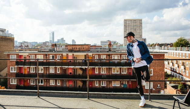 Tattooed man standing on a roof terrace looking out over a view of London