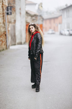 Beautiful young curly long haired woman wearing street style outfit in urban street