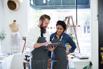 Co-workers looking at digital tablet inside small business artisan retail store