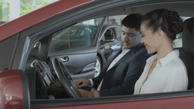 Happy woman gets the keys from salesman from a new car